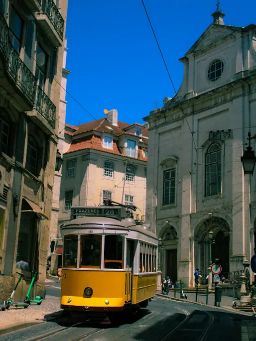 Tram jaune de la ligne 28 dans une rue pavée de Lisbonne